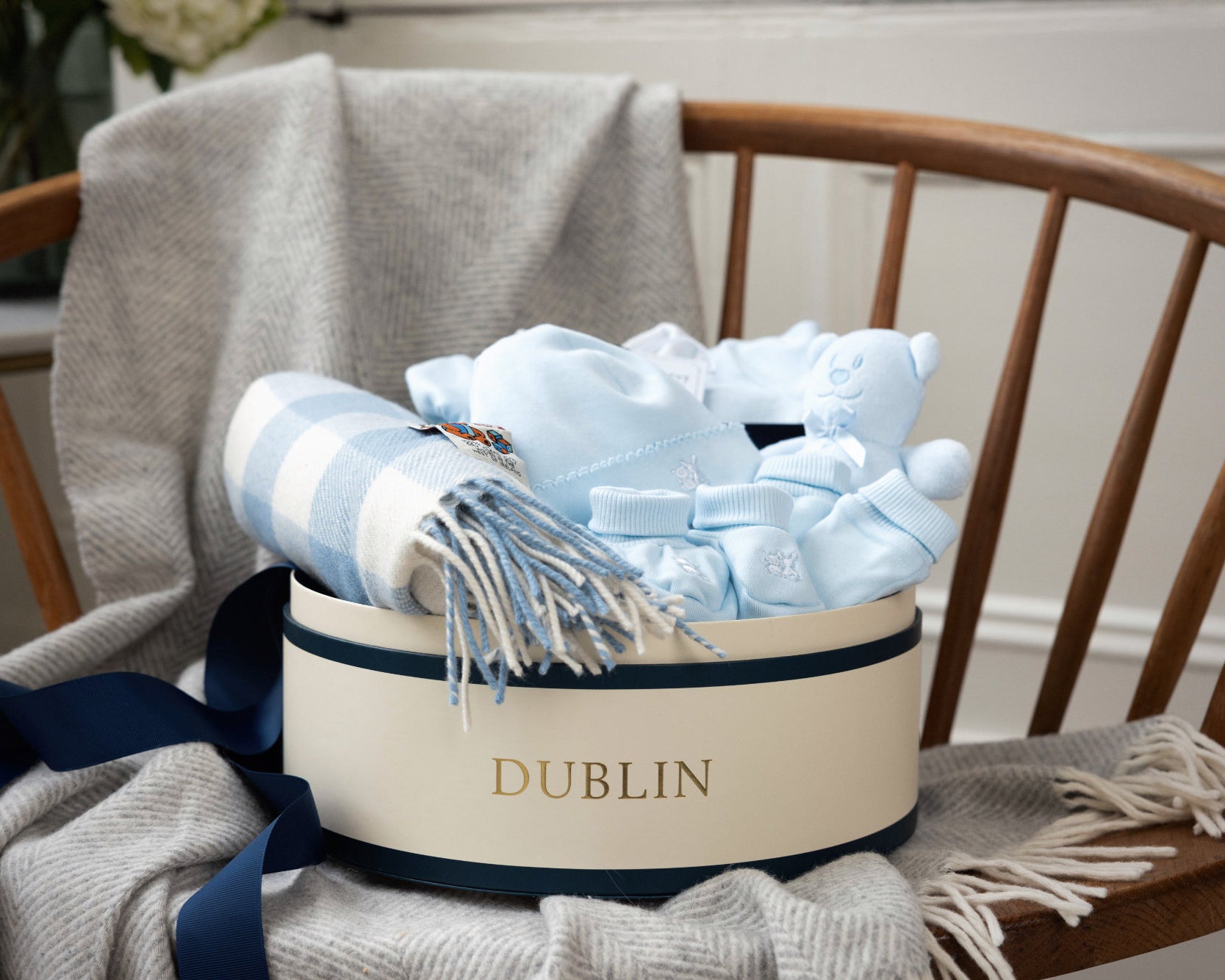 Gift basket with baby items including blankets and socks on a chair, branded 'Dublin'.