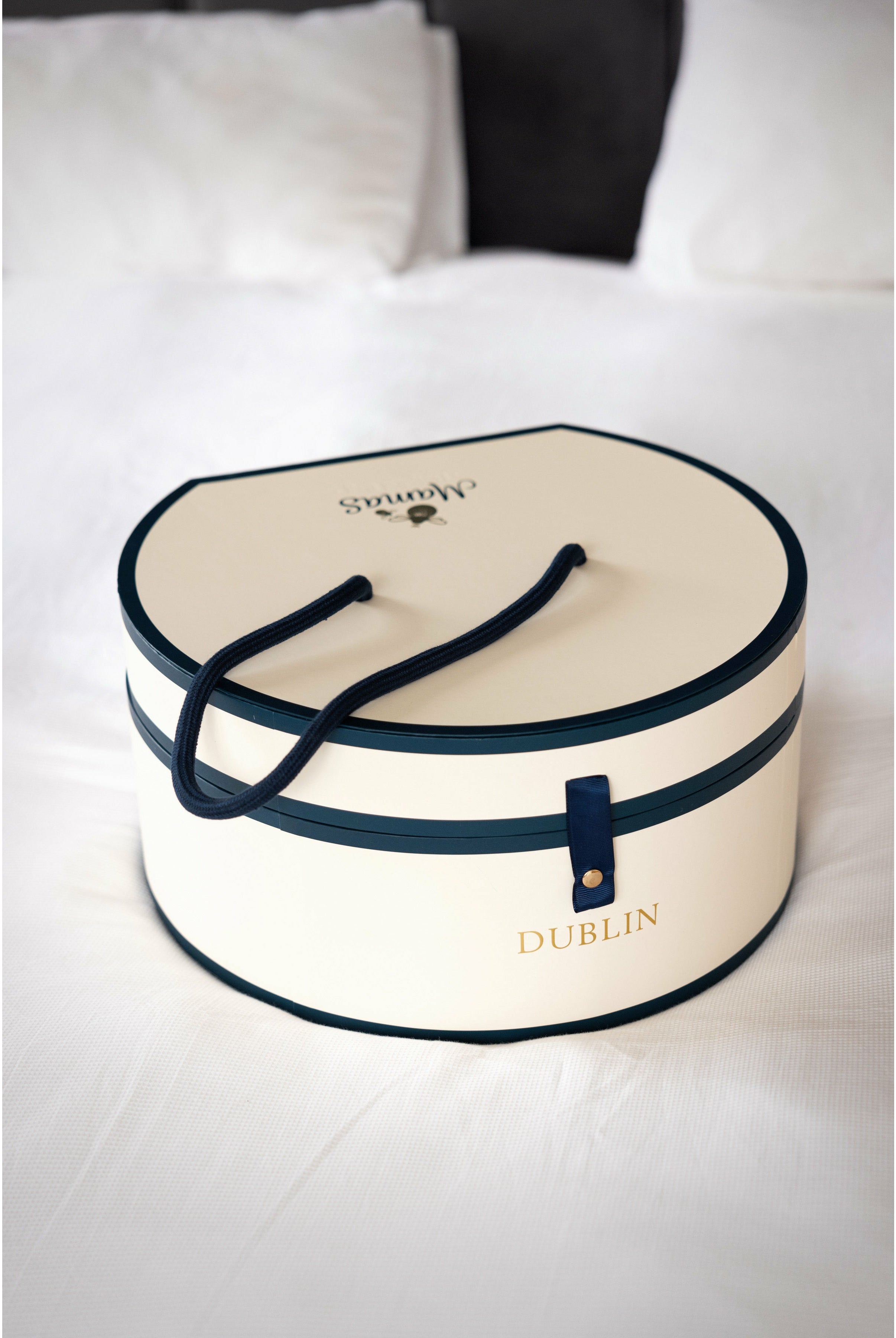 cream and navy Hat box gift box on white bed