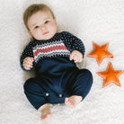 Baby lying on a textured surface with two orange stars nearby