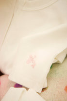 Close-up of a white garment with a pink logo on a textured surface