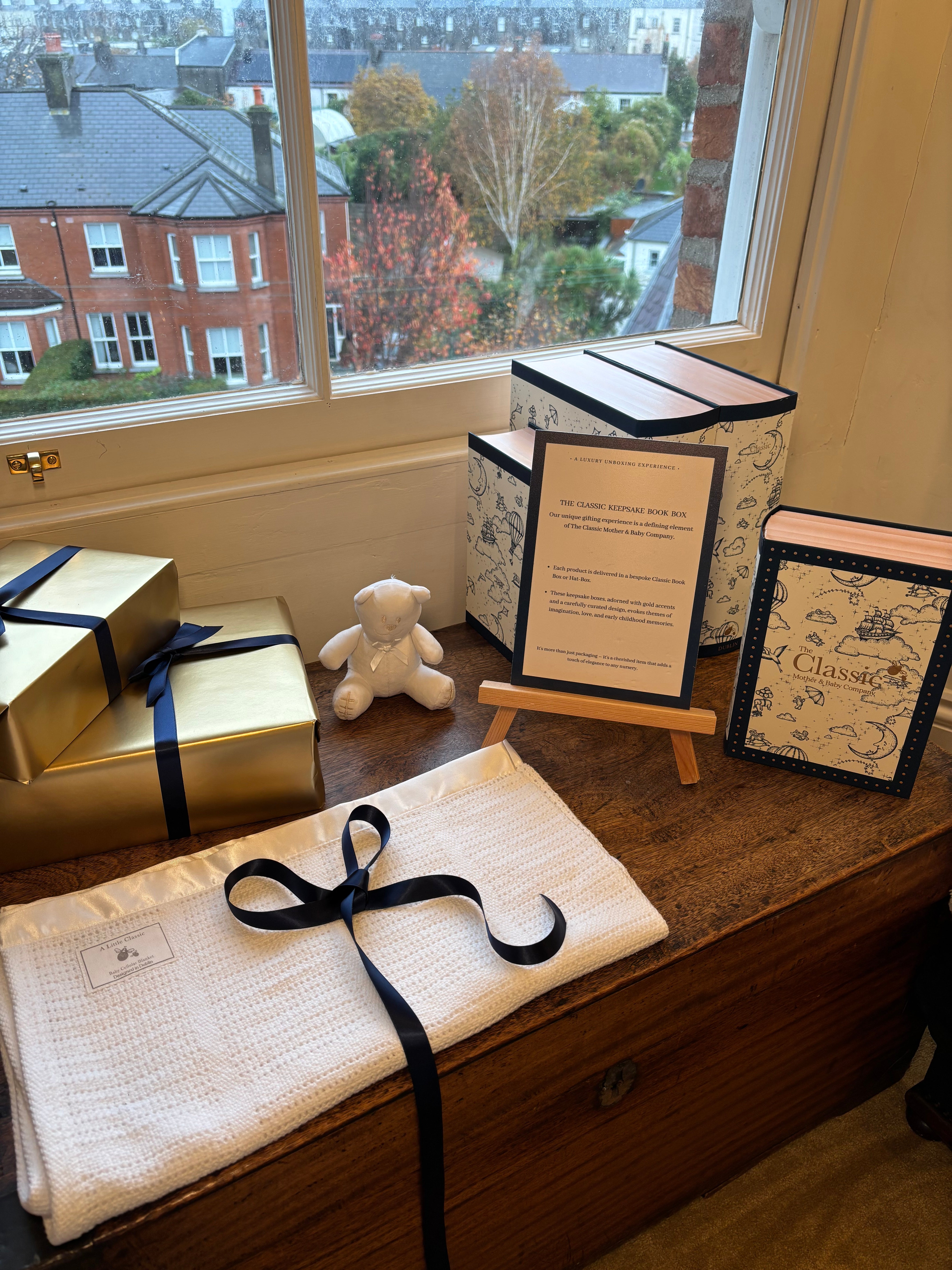 Gifts and decorative items on a table with a window view of buildings.