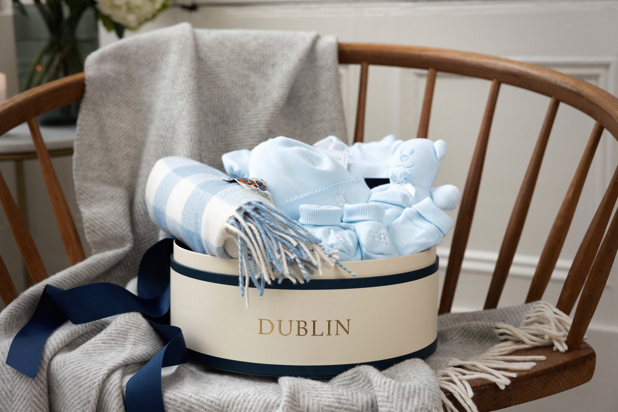 Gift basket with baby items including blankets and socks on a chair, branded 'Dublin'.