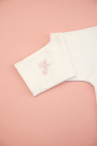 White towel with pink embroidery on a pink background