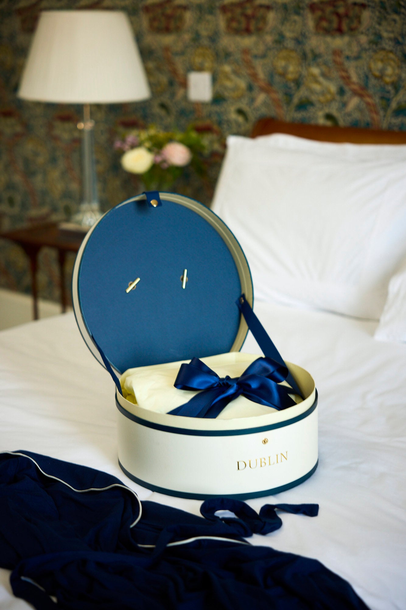 Navy jewelry box with a bow on a bed
